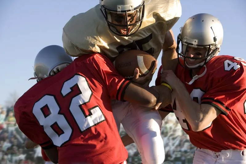 American football players tackling during a game