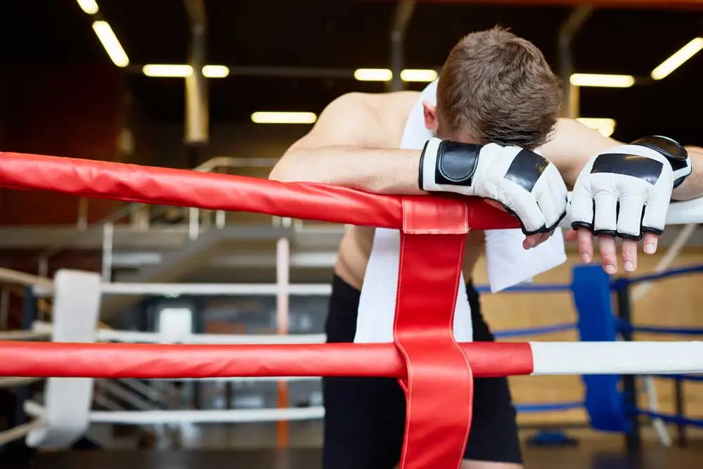 Defeated boxer leaning on ropes