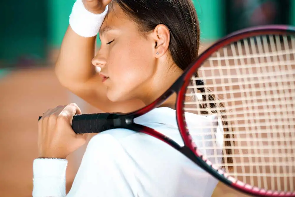 Tired girl tennis player wiping sweat