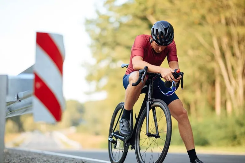 Cyclist resting with a racing bike beside the road