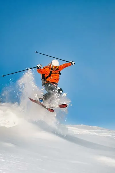 Person skiing down mountain on sunny winter day